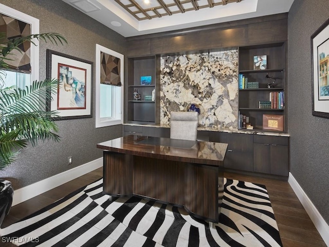 home office with dark hardwood / wood-style flooring and a tray ceiling