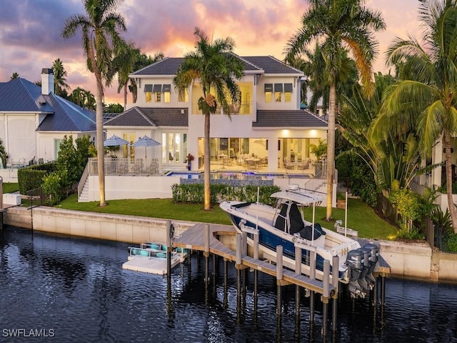 back house at dusk with a patio area and a water view