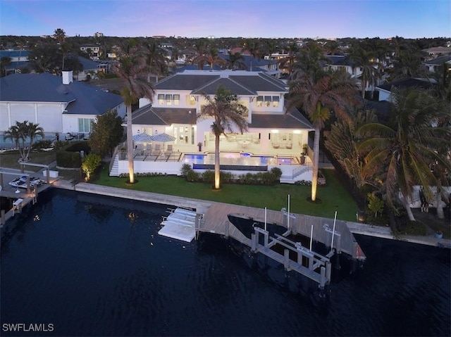 aerial view at dusk featuring a water view