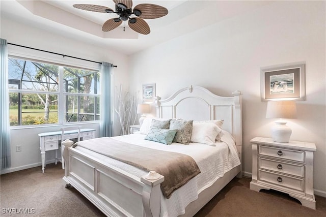 bedroom featuring dark carpet, a raised ceiling, and ceiling fan