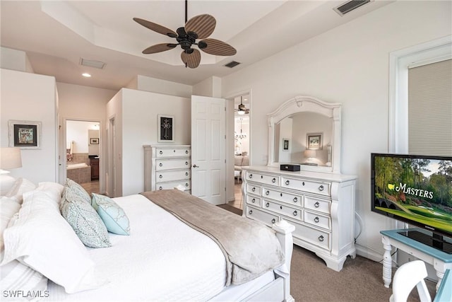 bedroom featuring carpet, connected bathroom, a tray ceiling, and ceiling fan