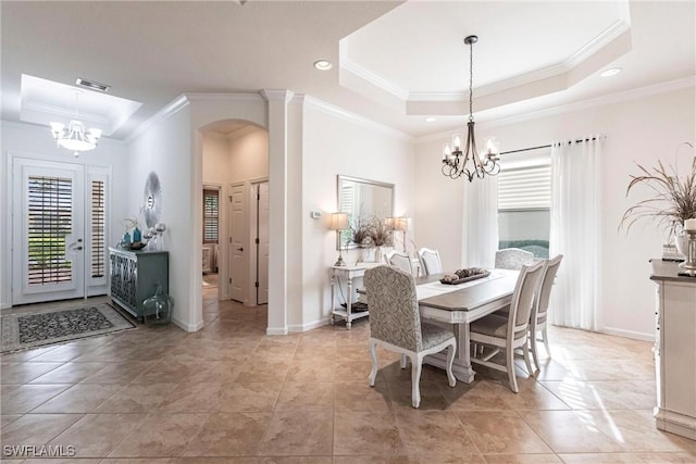 dining space featuring a raised ceiling, crown molding, and a notable chandelier