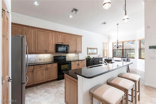 kitchen with a chandelier, a kitchen island with sink, pendant lighting, and black appliances