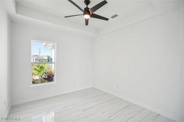 empty room featuring ceiling fan and a raised ceiling