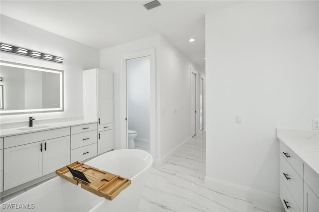 bathroom with a washtub, vanity, and toilet