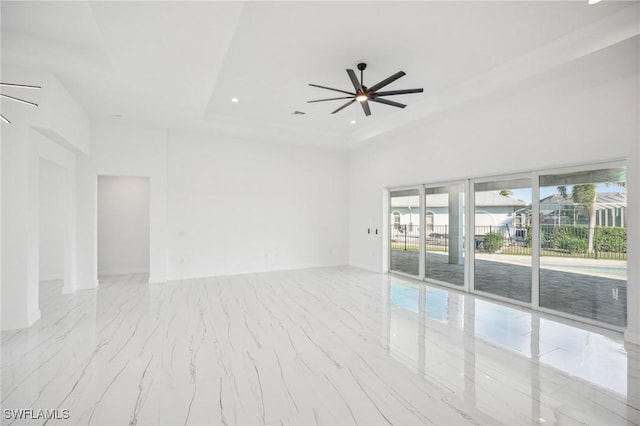 empty room featuring ceiling fan and a tray ceiling