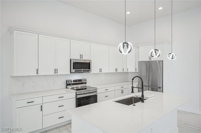 kitchen with a kitchen island with sink, hanging light fixtures, and appliances with stainless steel finishes