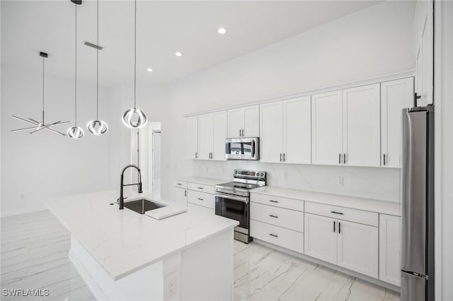 kitchen featuring decorative light fixtures, stainless steel appliances, white cabinetry, and a center island with sink