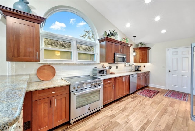 kitchen featuring decorative backsplash, stainless steel appliances, decorative light fixtures, and vaulted ceiling