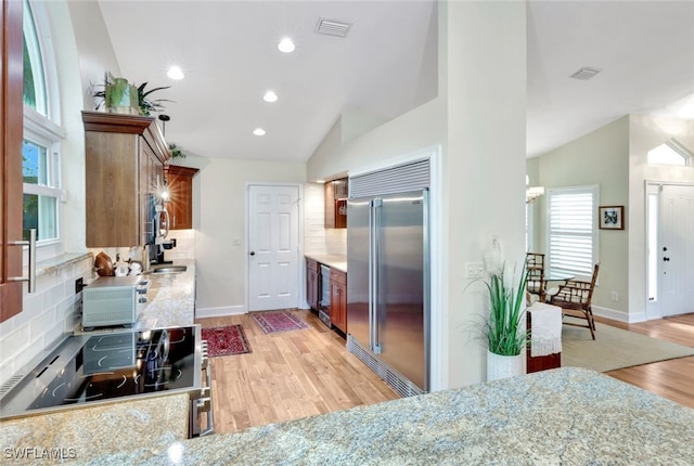 kitchen with decorative backsplash, appliances with stainless steel finishes, and vaulted ceiling