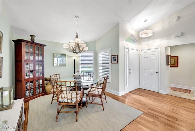 dining area with a chandelier, light wood-type flooring, and lofted ceiling