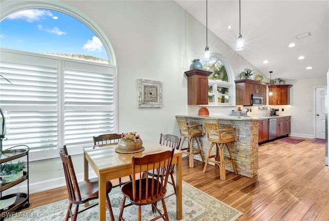 dining room with light hardwood / wood-style floors and high vaulted ceiling