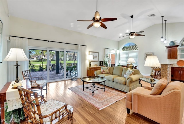 living room with ceiling fan, light hardwood / wood-style floors, and vaulted ceiling