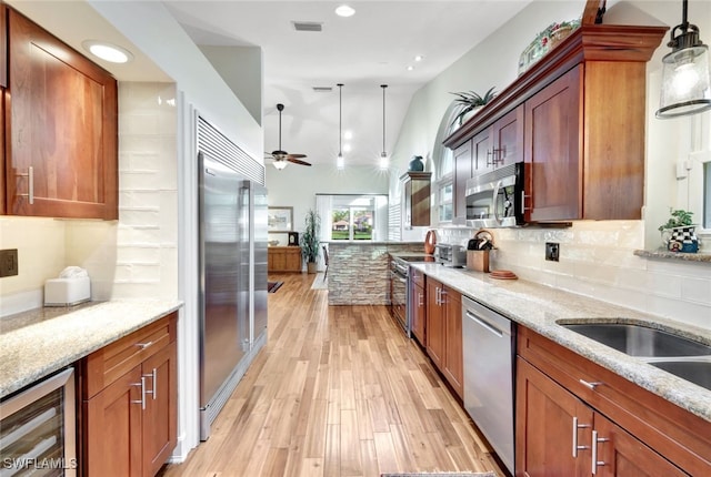 kitchen featuring light stone countertops, stainless steel appliances, ceiling fan, wine cooler, and hanging light fixtures