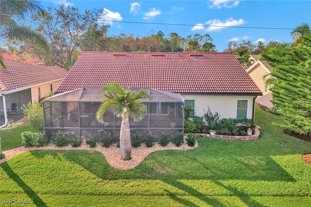 back of house featuring a lanai and a yard