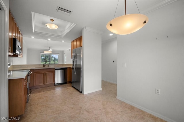 kitchen with ornamental molding, hanging light fixtures, appliances with stainless steel finishes, and a tray ceiling