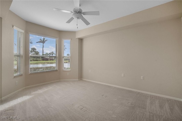 carpeted spare room with ceiling fan and a water view