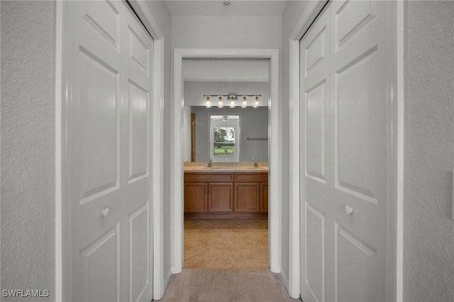 corridor with sink and light colored carpet