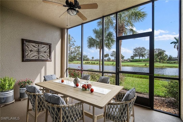 sunroom featuring ceiling fan and a water view