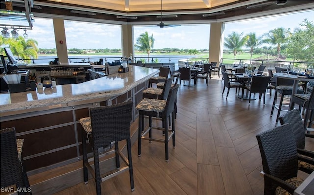 interior space with parquet flooring, light stone countertops, ceiling fan, decorative light fixtures, and a water view