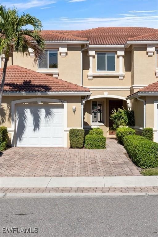 view of property featuring a tiled roof, decorative driveway, and stucco siding