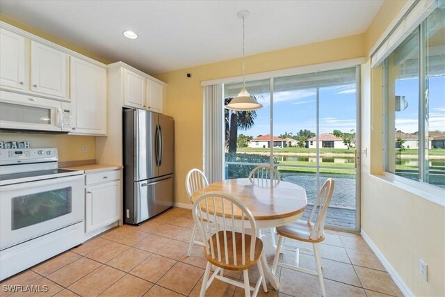 kitchen featuring white cabinetry, a healthy amount of sunlight, white appliances, light tile patterned flooring, and hanging light fixtures