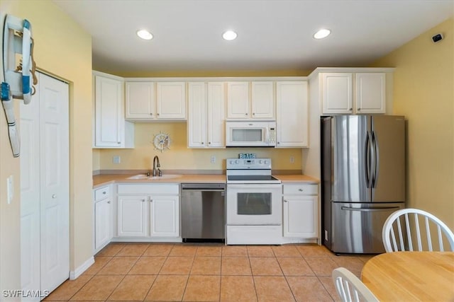 kitchen with light tile patterned floors, sink, white cabinetry, and appliances with stainless steel finishes