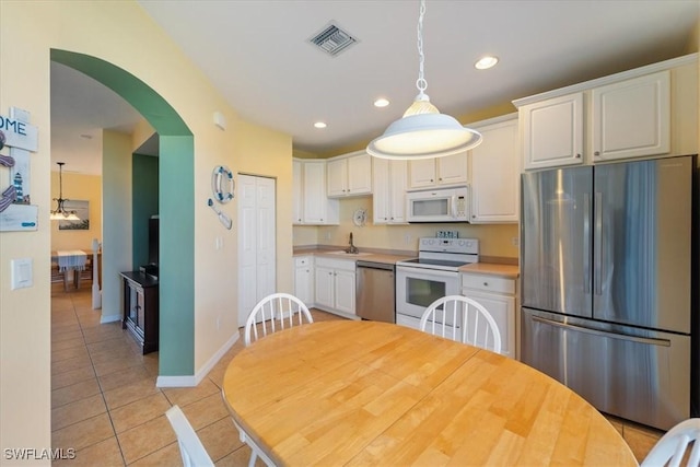 kitchen featuring decorative light fixtures, white cabinets, appliances with stainless steel finishes, and light tile patterned floors