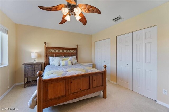 carpeted bedroom featuring ceiling fan and two closets