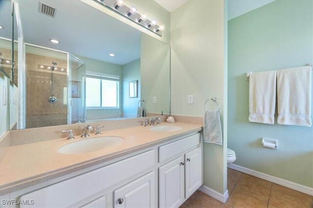 bathroom with toilet, tile patterned flooring, a shower with shower door, and vanity