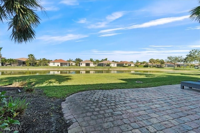 view of home's community with a water view, a yard, and a patio