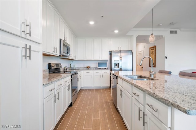 kitchen featuring appliances with stainless steel finishes, white cabinetry, crown molding, and sink