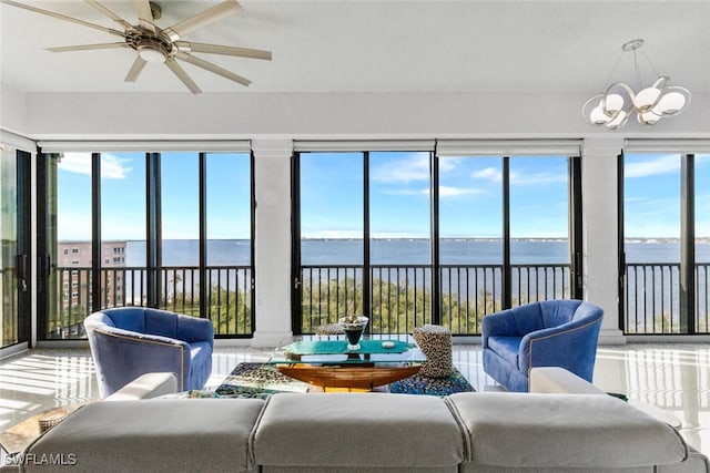 sunroom featuring ceiling fan with notable chandelier, a healthy amount of sunlight, and a water view