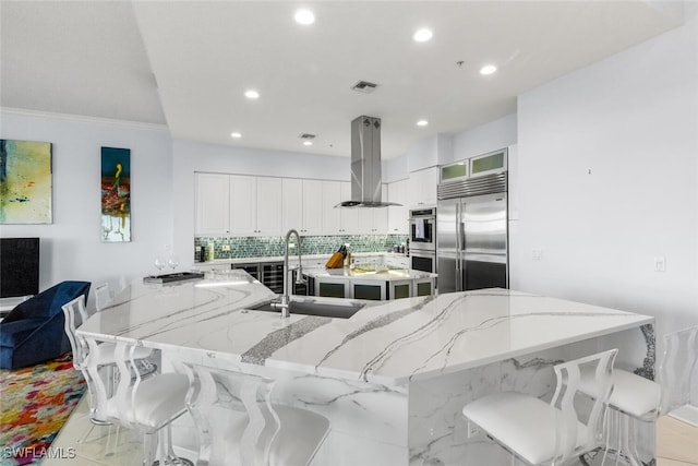 kitchen with sink, stainless steel appliances, island exhaust hood, and light stone countertops