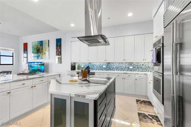 kitchen featuring built in fridge, light stone countertops, a center island, white cabinetry, and island exhaust hood