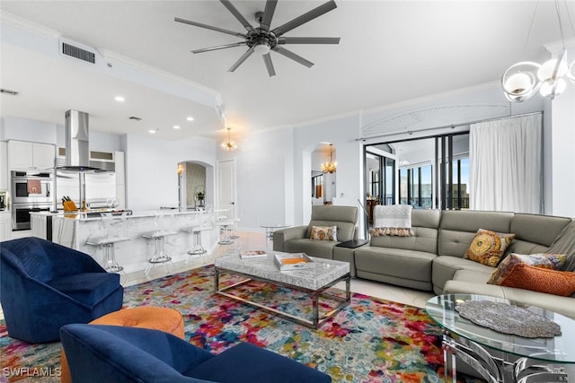 tiled living room featuring ceiling fan with notable chandelier and ornamental molding