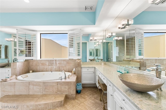 bathroom featuring vanity, tiled bath, and tile patterned flooring