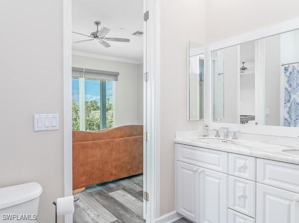 bathroom featuring toilet, hardwood / wood-style flooring, ceiling fan, ornamental molding, and vanity