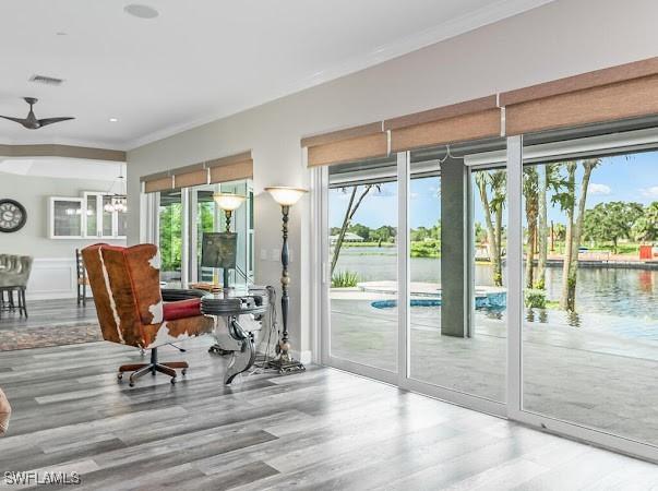 doorway featuring ceiling fan with notable chandelier, crown molding, a water view, and hardwood / wood-style floors