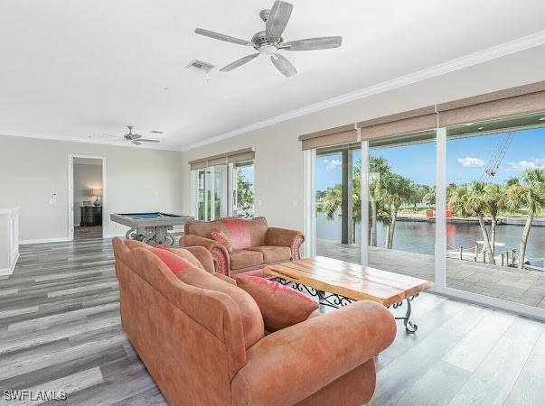 living room with ceiling fan, wood-type flooring, crown molding, and a water view