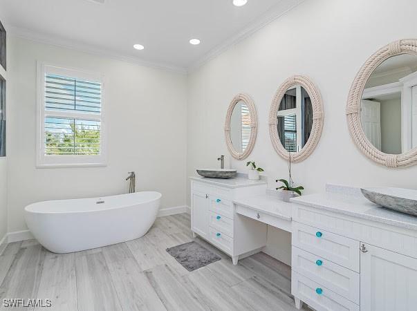 bathroom featuring ornamental molding, a tub to relax in, hardwood / wood-style flooring, and vanity