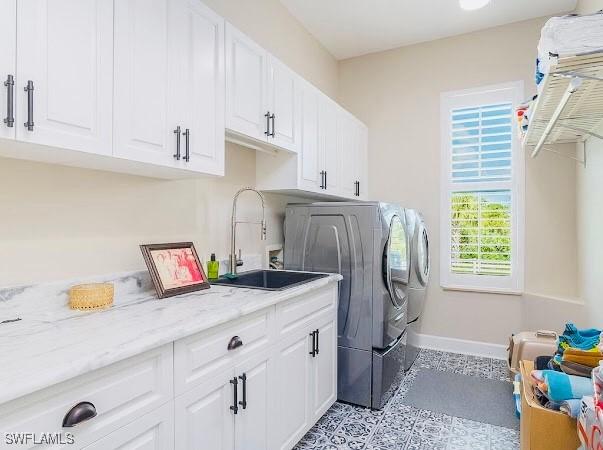 laundry area with washing machine and dryer, cabinets, and sink