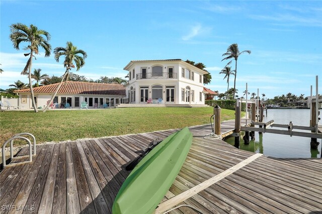 view of dock with a water view, a balcony, a yard, and a patio area