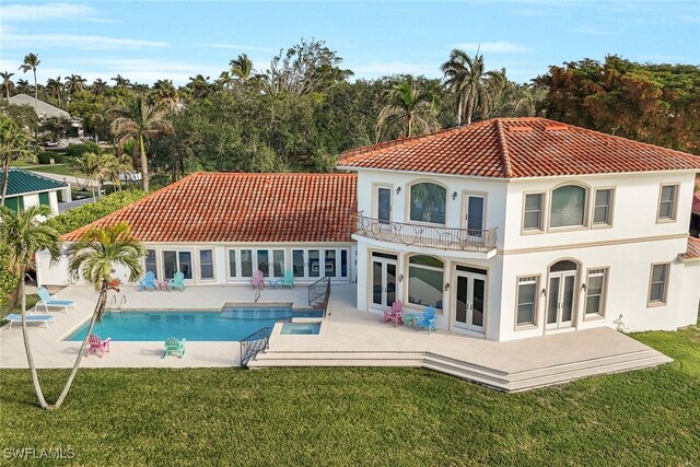 rear view of house with french doors, a tile roof, a yard, a patio area, and a balcony