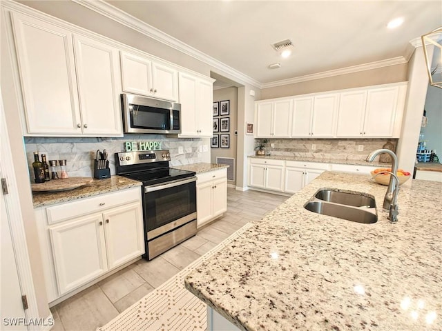 kitchen with white cabinets, appliances with stainless steel finishes, light stone counters, and sink