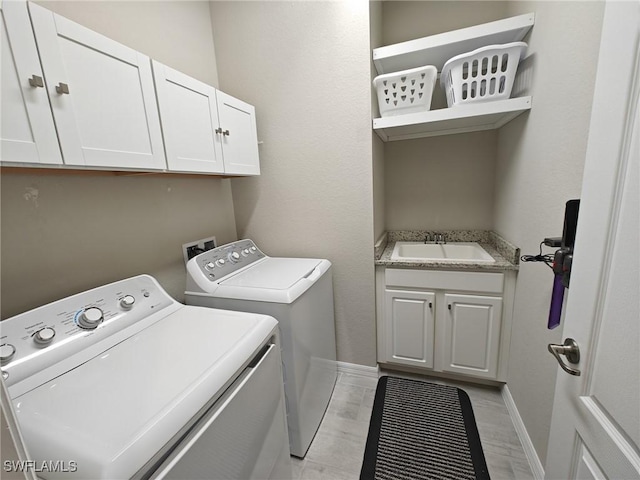 clothes washing area with cabinets, separate washer and dryer, and sink