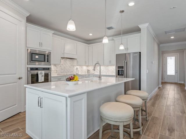 kitchen featuring sink, white cabinets, a kitchen island with sink, and appliances with stainless steel finishes