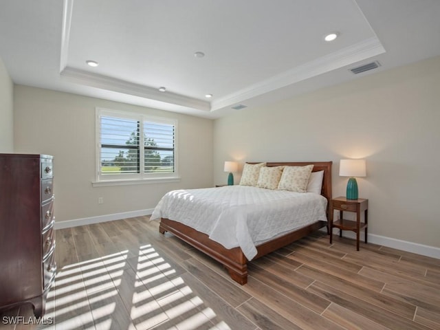 bedroom with hardwood / wood-style flooring and a tray ceiling