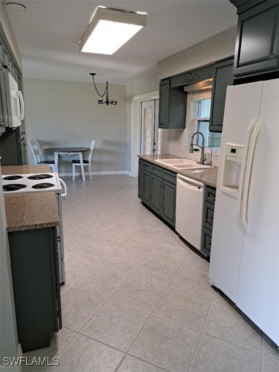 kitchen with light tile patterned floors, white appliances, an inviting chandelier, and sink