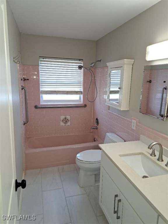 full bathroom with tasteful backsplash, vanity, tiled shower / bath combo, tile walls, and toilet